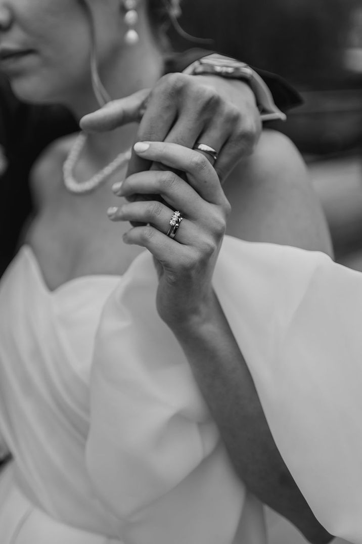 Bride reaching up to hold the groom's hands wearing trinity stone engagement ring 