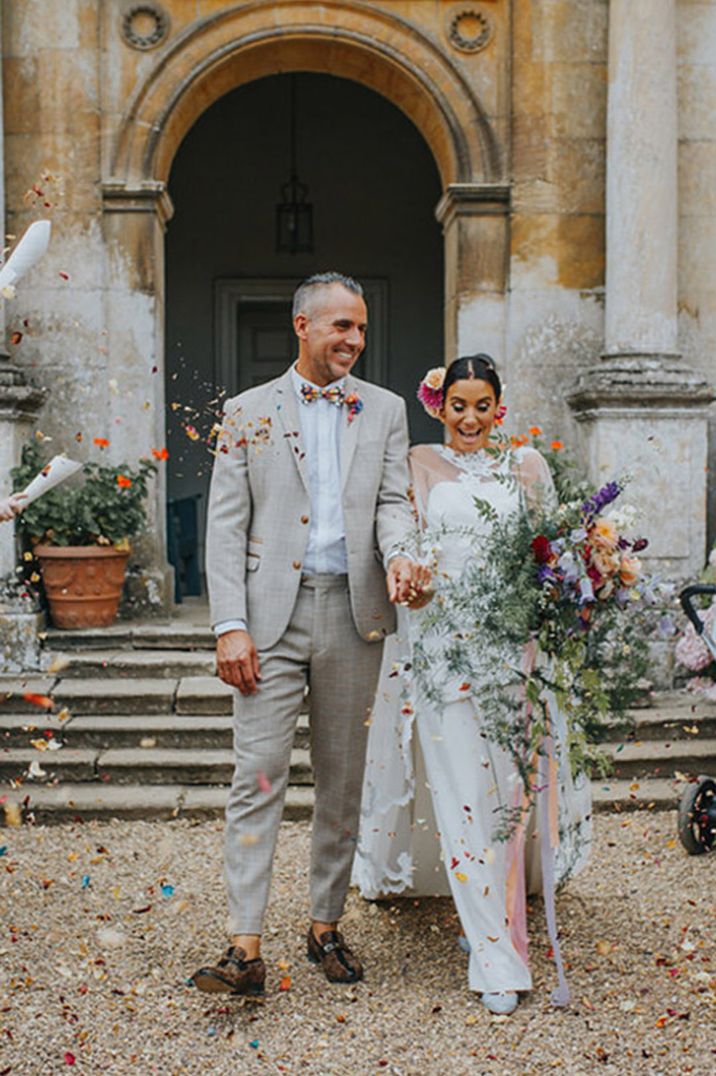 Groom in light grey wedding suit walking with the bride as they have their confetti exit from the vow renewal ceremony 