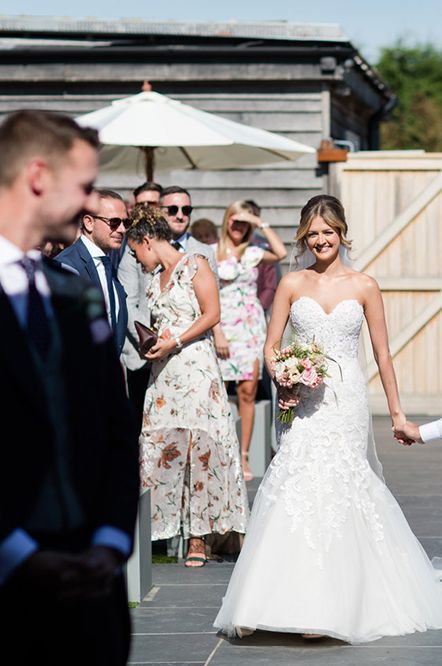 A bride walks down the aisle with her dad who is in a wheelchair at accessible wedding venue Southend Barns. 