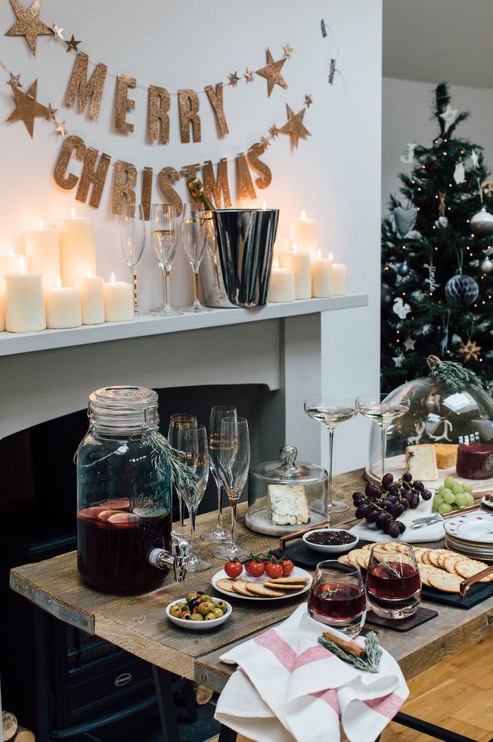 Merry Christmas sign, mulled wine, decorated Christmas tree, champagne, and pillar candles at Christmas soiree