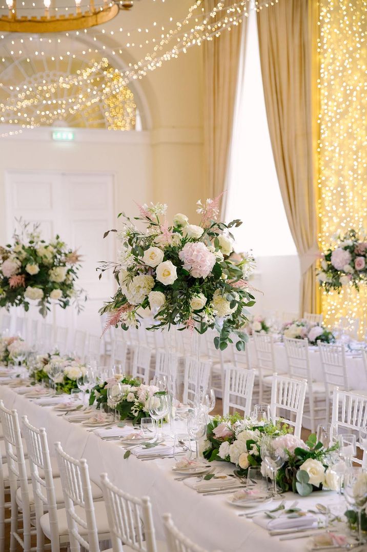 Pink and white large table centrepieces and runner on white tablecloth at luxury castle wedding venue 