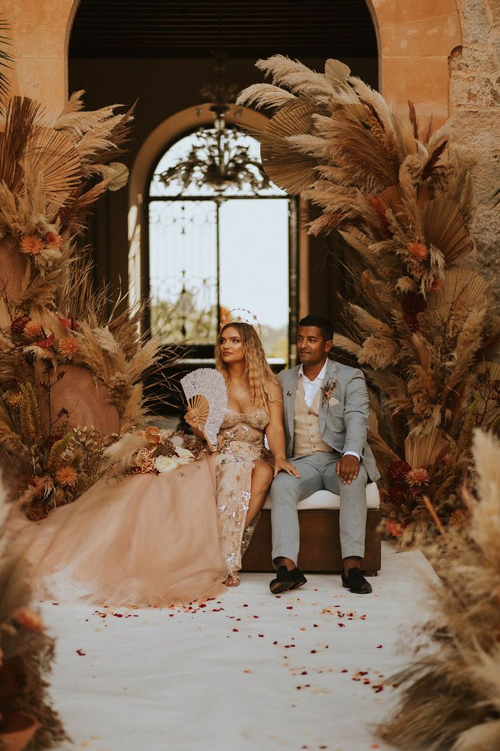 Bride and groom sit next to their pampas grass columns for celestial wedding 