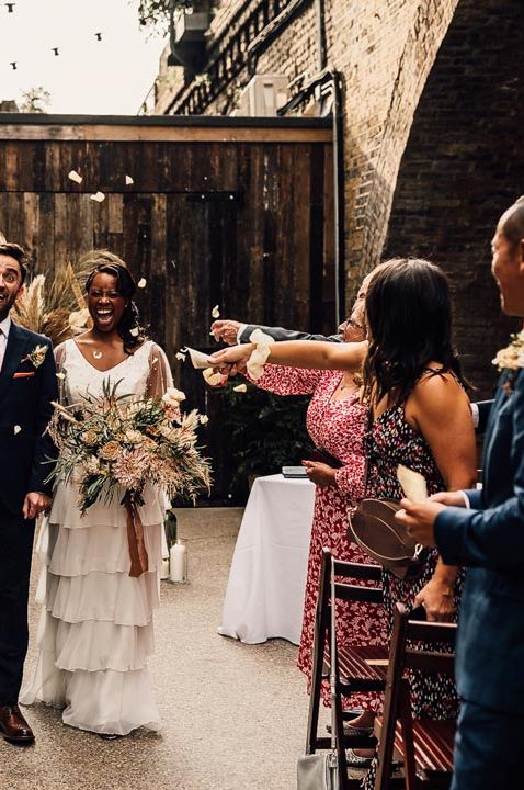 Bride in tulle layered dress with neutral bouquet and groom in dark suit with red tie at 100 Barrington