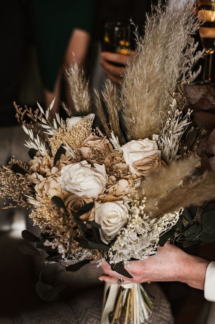 Beautiful neutral preserved wedding flower bridal bouquet with white roses and dried grass 