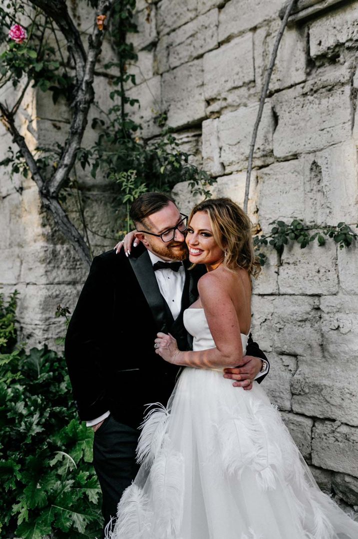 Destination wedding in France with the groom in a black tux and the bride in a feather wedding dress 