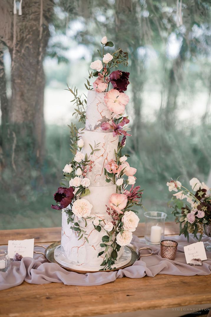 Four tier marble effect wedding cake with pink and purple wedding flower decorations for incredible botanical wedding 