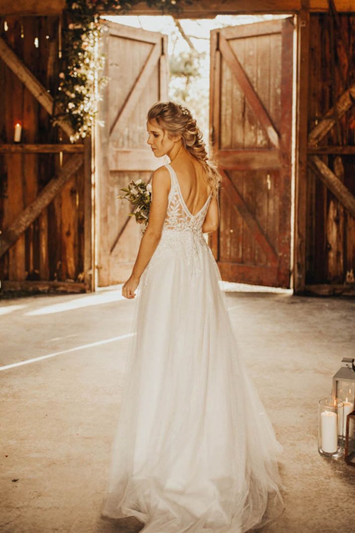 Bride with elegant blonde braid hairstyle in lace wedding dress at barn wedding venue