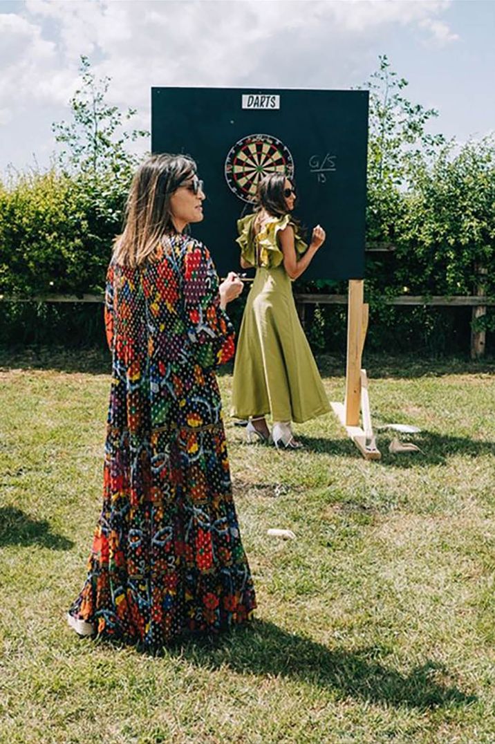 Wearing guests wearing summer wedding guest dresses while playing darts during outdoor wedding by Lee Allison Photography