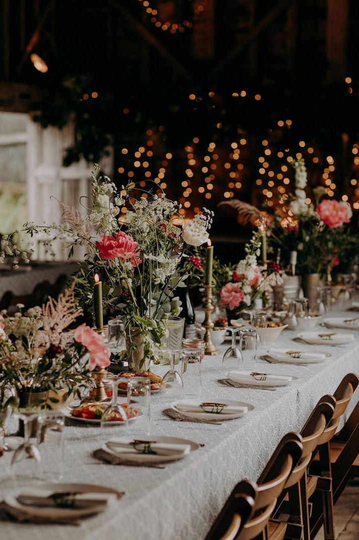 Neutral themed wedding tablescape with green candles and touches of pink flowers at DIY barn wedding