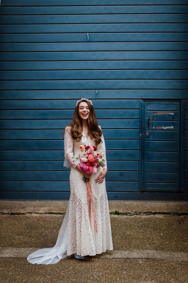 The bride wears a boho lace wedding dress from Rixo with shoulder pads and a leg split detail 