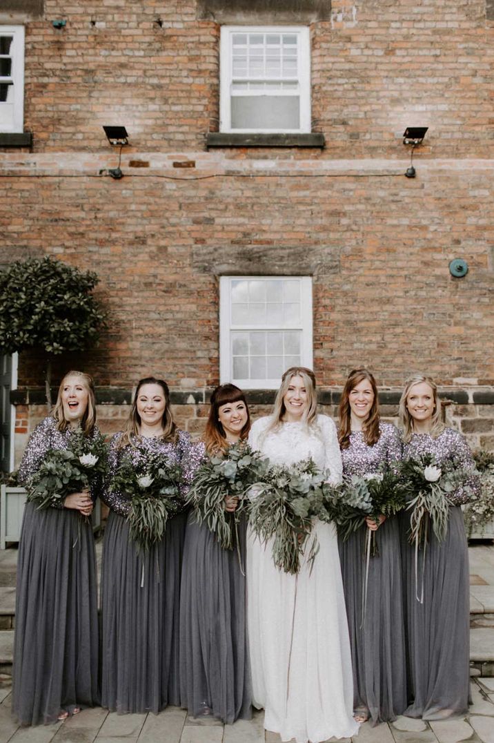 Bridesmaids in charcoal grey long sleeve dresses for a foliage winter wedding with bride in long sleeve wedding dress 