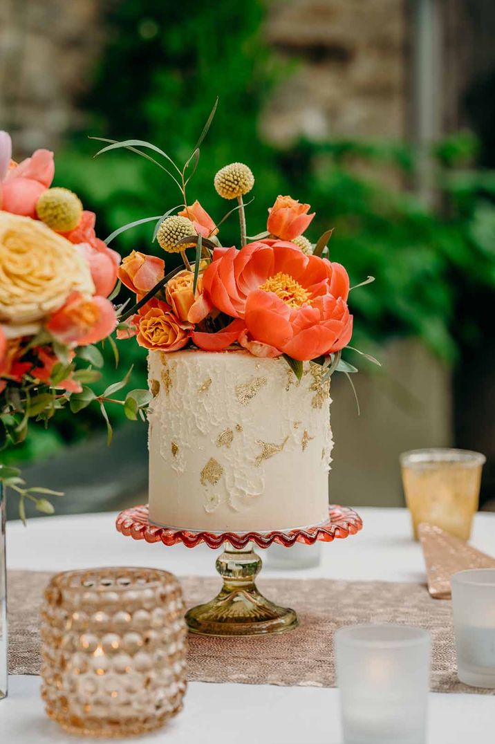 Single tier wedding cake with coral peony cake topper flower