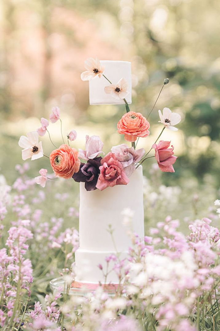 Tall white iced floating wedding cake with floral decoration 