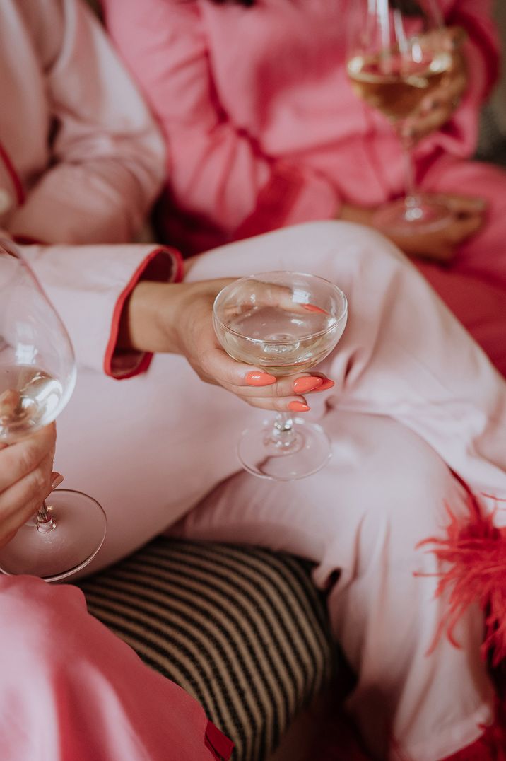 Bride wearing light pink bridal pyjamas with bright pink coral almond shaped wedding nails 