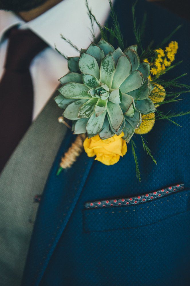 Groom in a navy suit with succulent buttonhole and yellow flower 