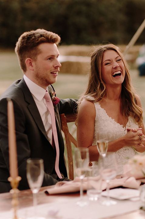 Bride in V-neck lace wedding dress listening to maid of honour speech