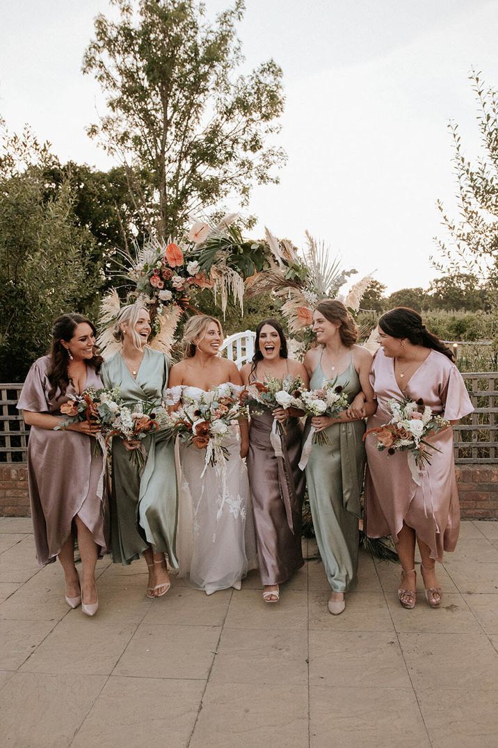 Bride in off the shoulder wedding dress walking with the bridesmaids in pink and sage green mismatched bridesmaid dresses 