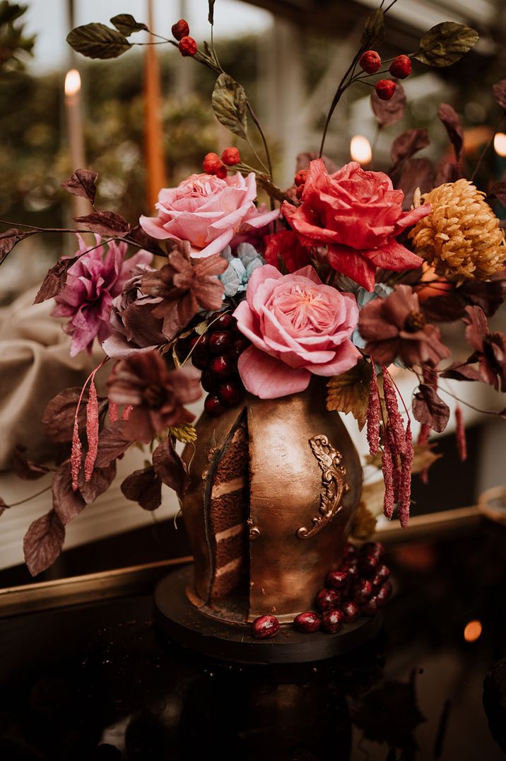 Realistic wedding cake as a golden vase with flowers coming from the top 