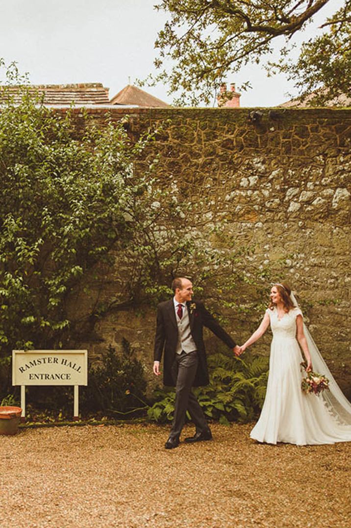 The bride and groom walk next to the Ramster Hall wedding sign 