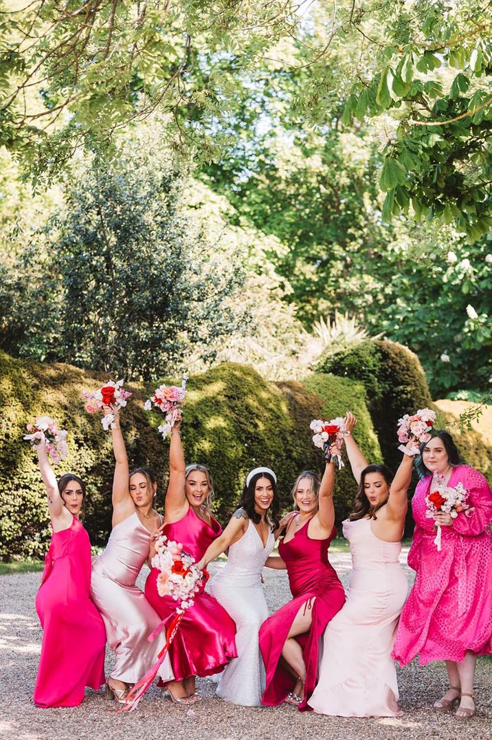 Bridal party wearing bright hot pink bridesmaid dresses with the bride in a sparkly wedding dress and headband 