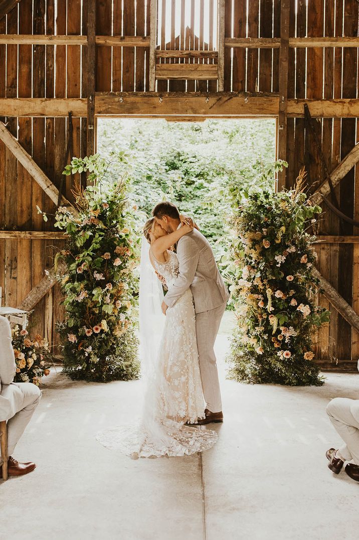 Two flower columns decorate the altar as the bride and groom share their first kiss as a married couple 