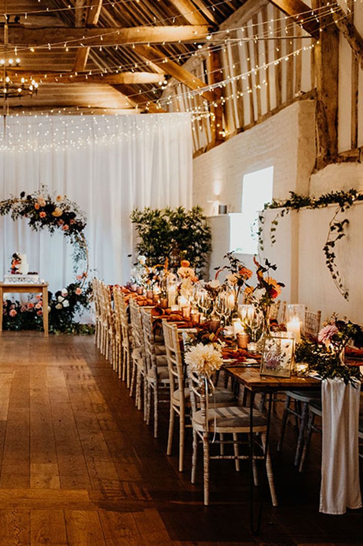 Orange and white flower wedding decorations with fairy lights and wedding cake in moon gates 