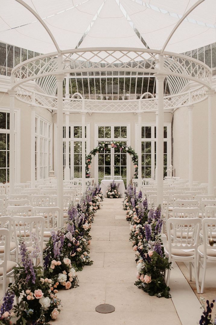 Purple and white epic aisle flower arrangements lining the aisle at the wedding venue