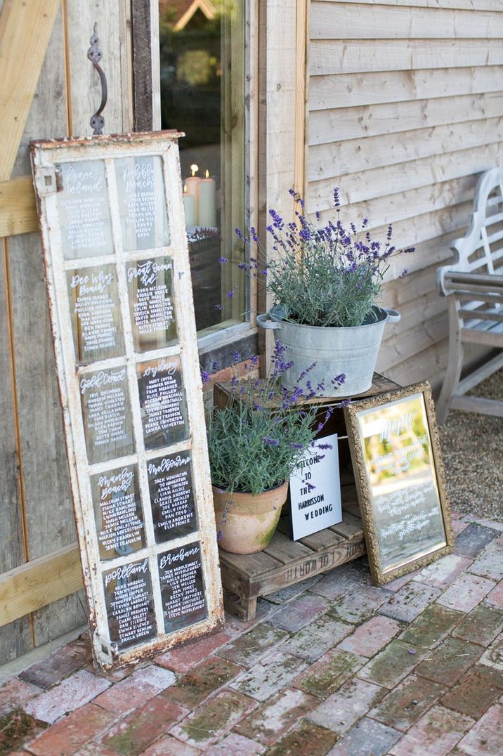 Rusted window frame seating chart with white font using a paint pen 