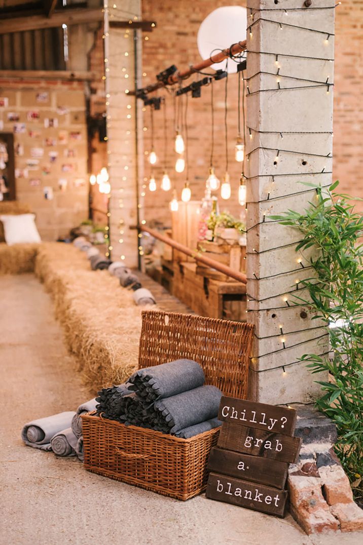 Wicker basket full of grey blankets for the wedding guests to wrap up with 