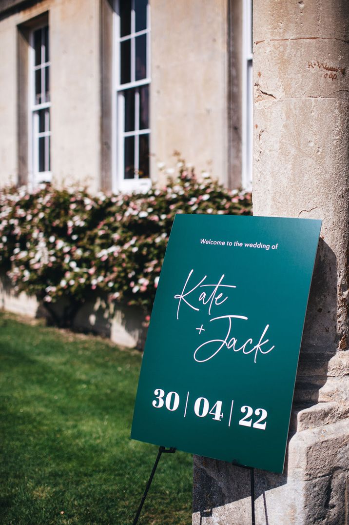 Green and white wedding welcome sign placed at the entrance to the wedding venue 