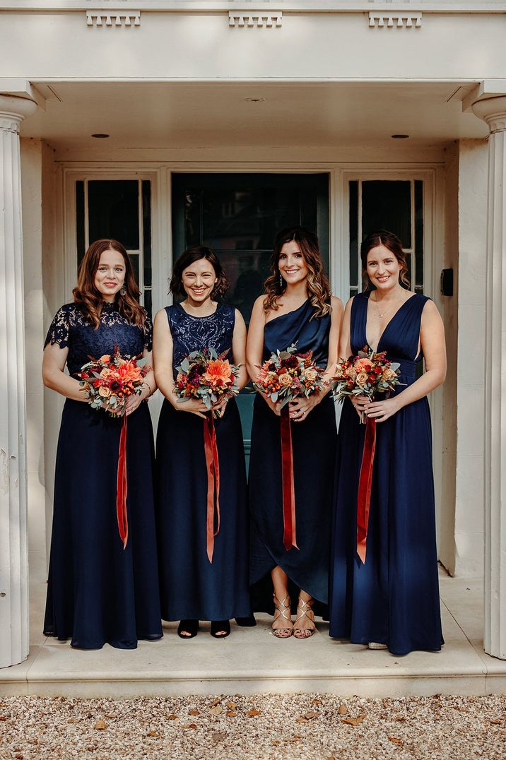 Bridal party portrait in different navy gowns including lace and satin bridesmaid dresses 