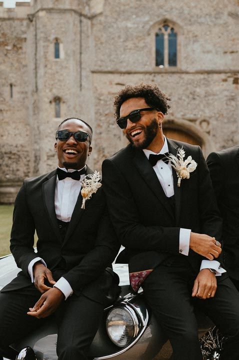 Groomsmen in matching suits and sunglasses standing by a convertible classic wedding car 