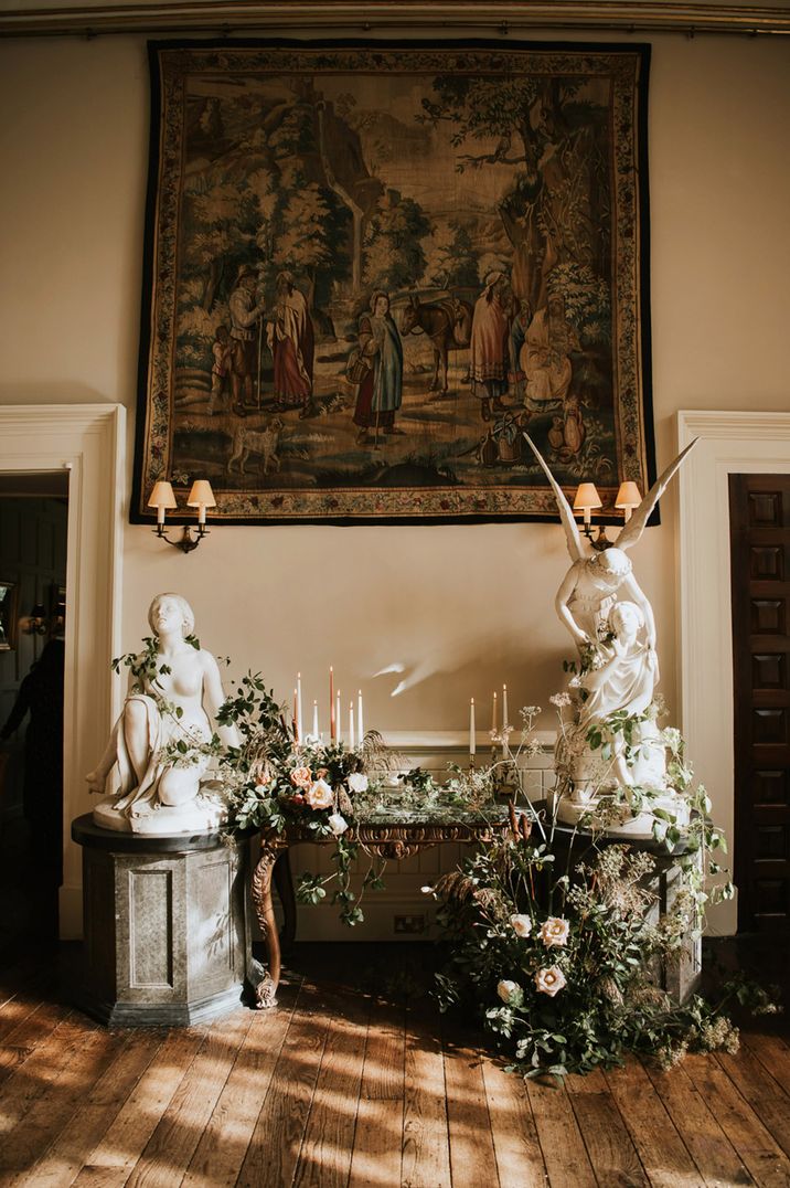 Large hanging rug, white statues and neutral toned foliage with light candles decor at Elmore Court