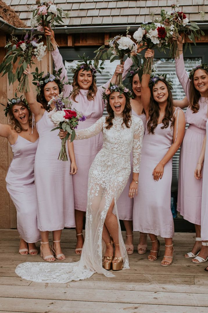 Bride in long sleeve lace wedding dress with bridesmaids in mismatched pink bridesmaid dresses 