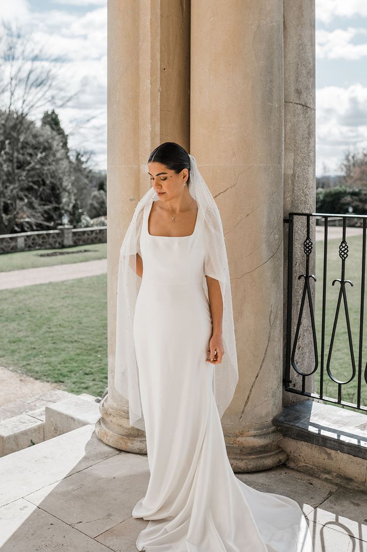 Bride wearing dropped waist wedding dress with square neckline and pearl wedding veil 