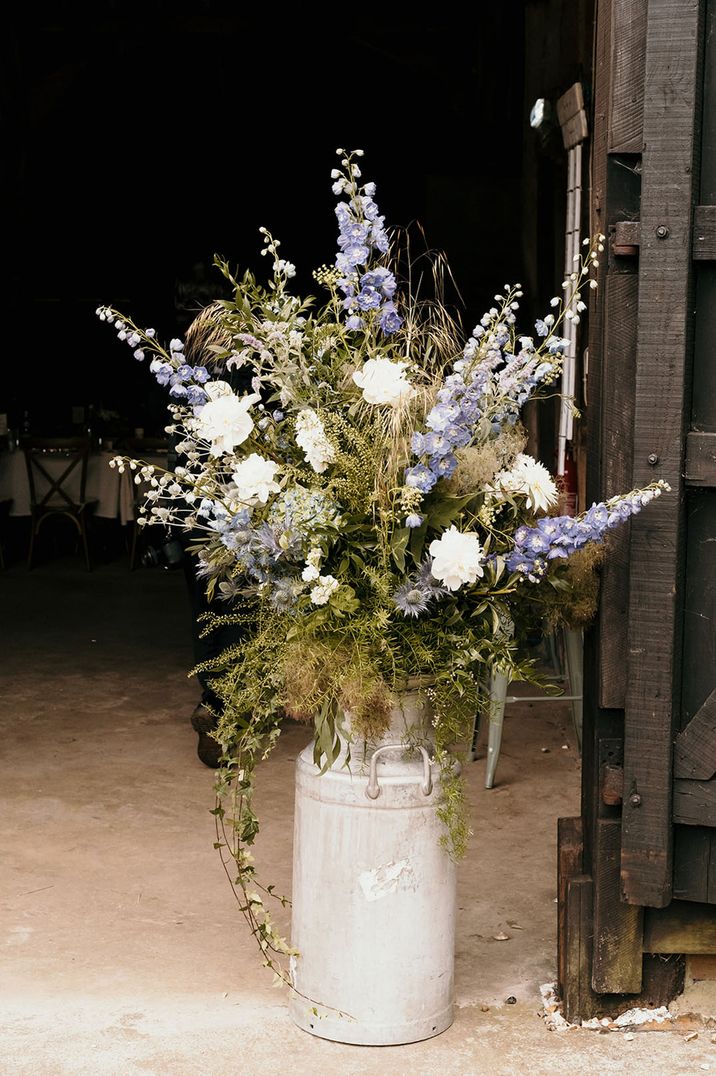 Milk churn wedding flower arrangement with Larkspur purple and white flowers 