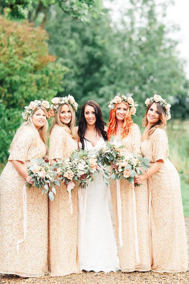 Bridesmaid wearing peach bridesmaid dresses holding bouquets and posing with bride on wedding day