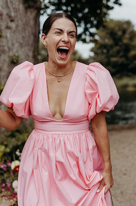 Wedding guests wearing baby pink and lilac dresses smiling widely 