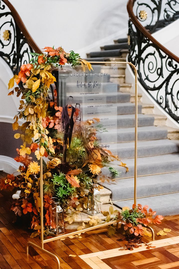 Order Of The Day acrylic sign on a gold metal frame surrounded by autumn leaves and flowers 