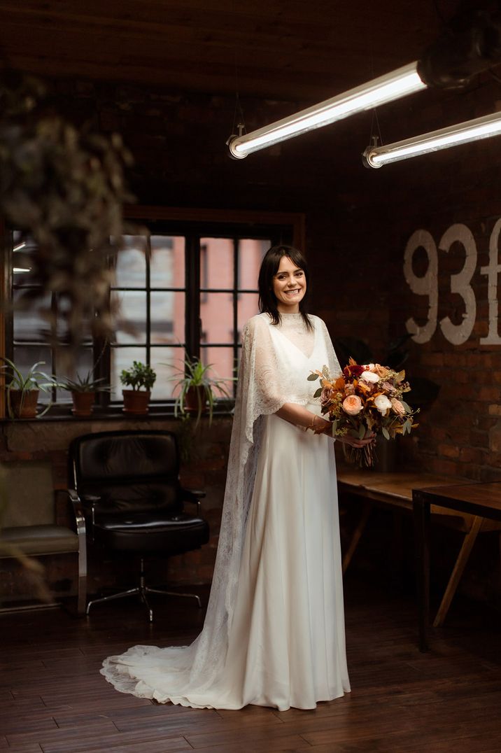 Bride in v-neck wedding dress with lace bridal cape for industrial wedding