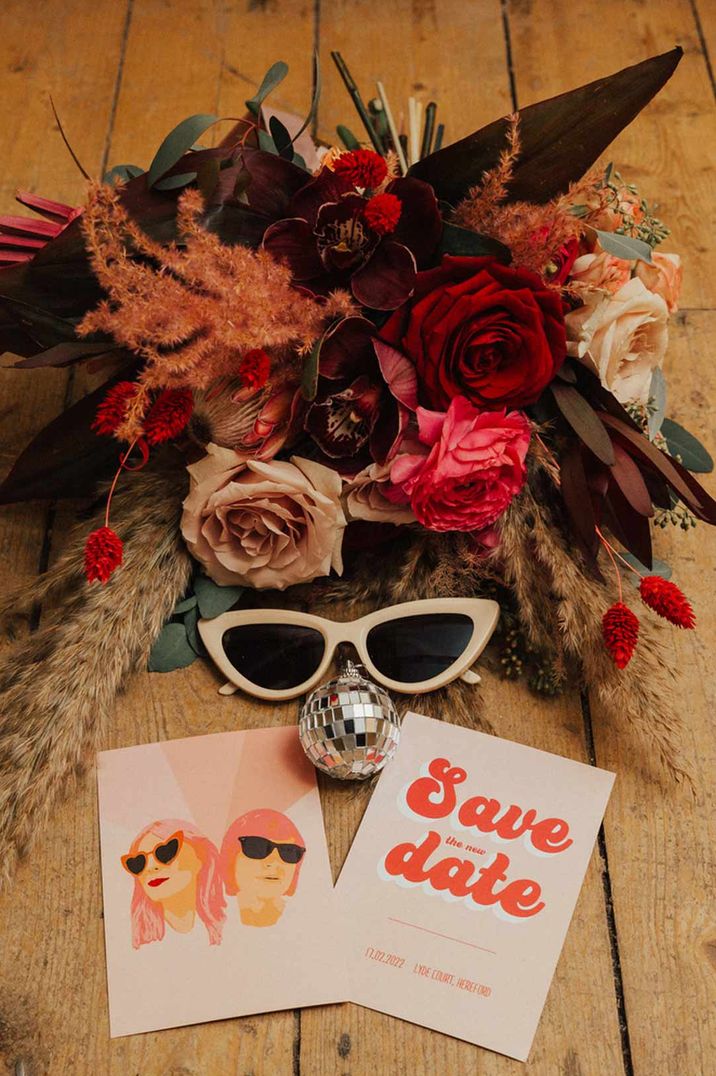 Pink and red wedding bouquet with retro style stationery and sunglasses at gender neutral wedding