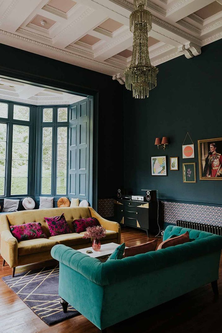 Netherbyres House wedding venue Scotland with deep teal and olive green velvet sofas, alternative crystal chandelier and bay windows overlooking manicured lawns