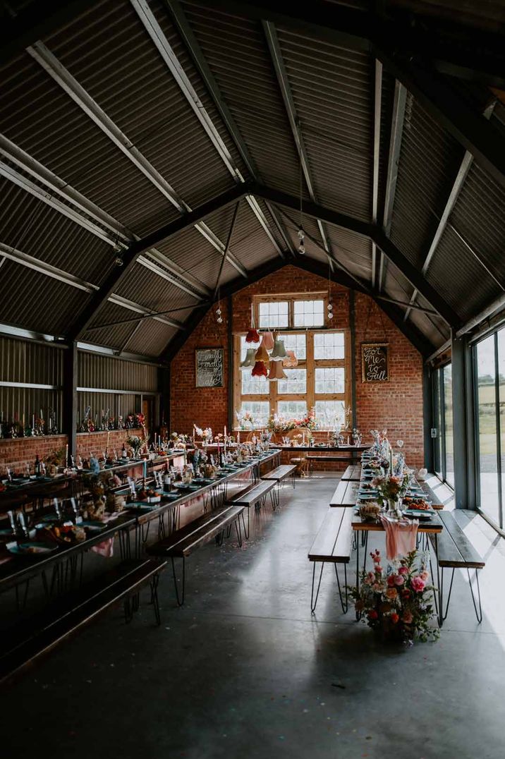 Reception room of The Giraffe Shed wedding venue with suspended lamp shade decorations and rustic wedding tablescapes 