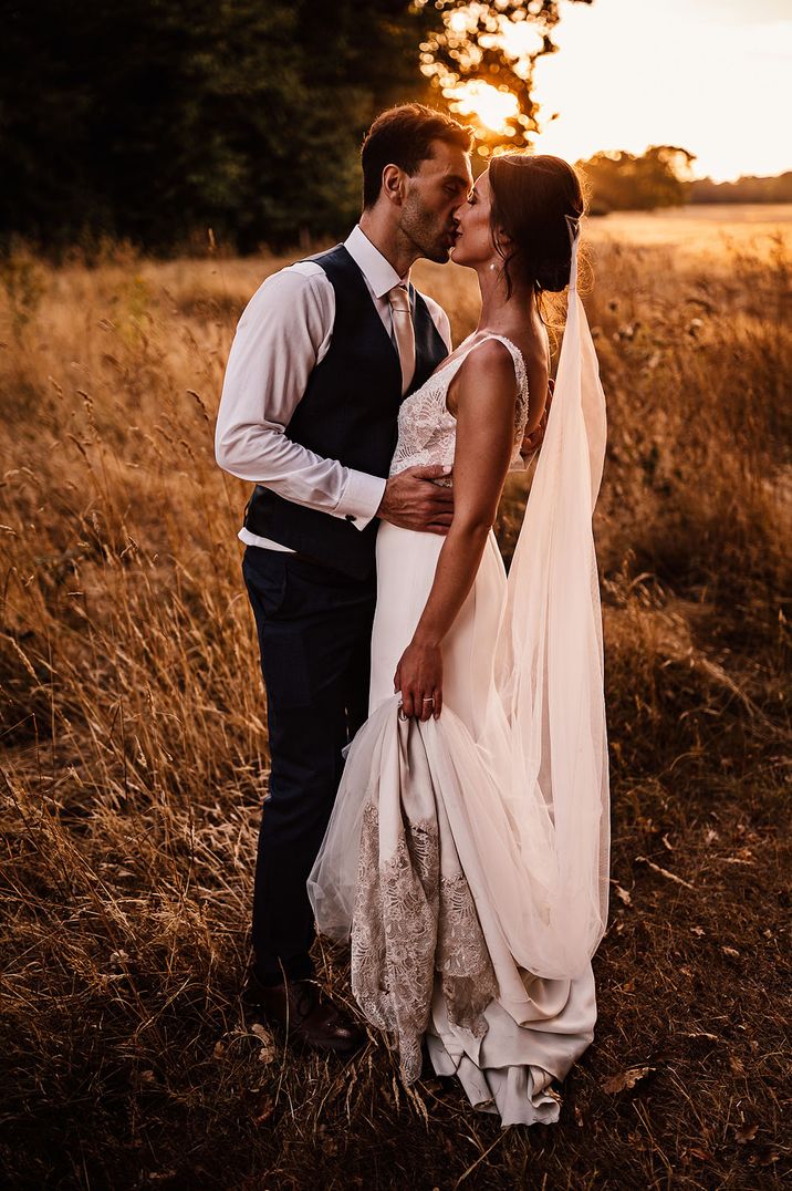 Bride in Enzoani wedding dress posing with groom during the famous golden hour 