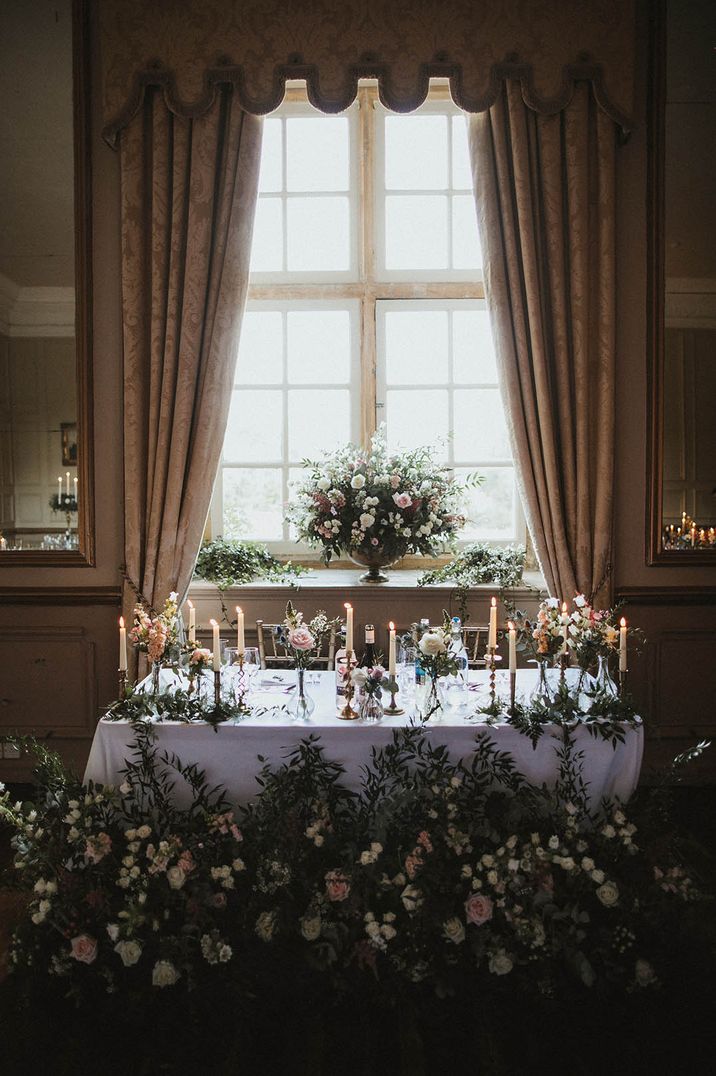 A classic country house wedding with traditional white wedding flower decorating a table for bride and groom 