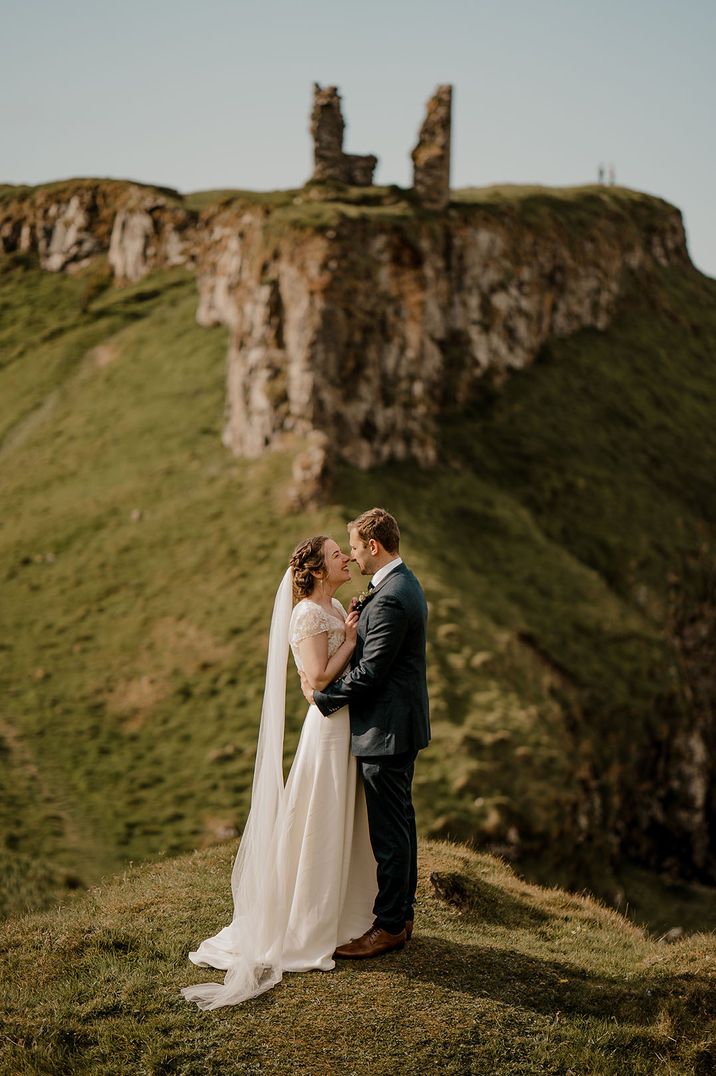 Dunluce Castle ruins wedding venue in Northern Ireland with bride and groom embracing 