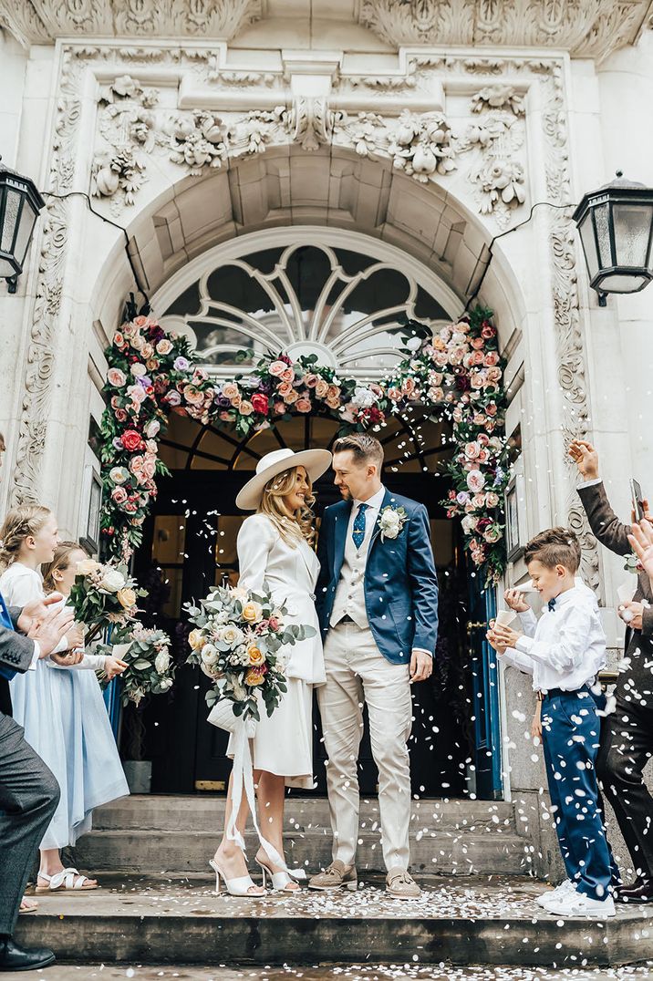 Confetti moment on the steps of Chelsea Town Hall with floral arch and bride in a vintage skirt suit belonging to her mother 