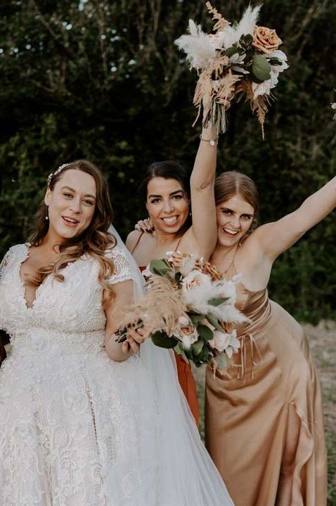 Bride in homemade short sleeve lace wedding dress and bridesmaids in DIY orange and red satin bridesmaid dresses