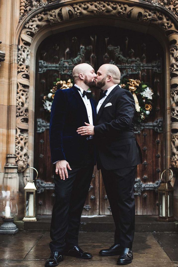 Grooms in black tie share a kiss for their wedding 