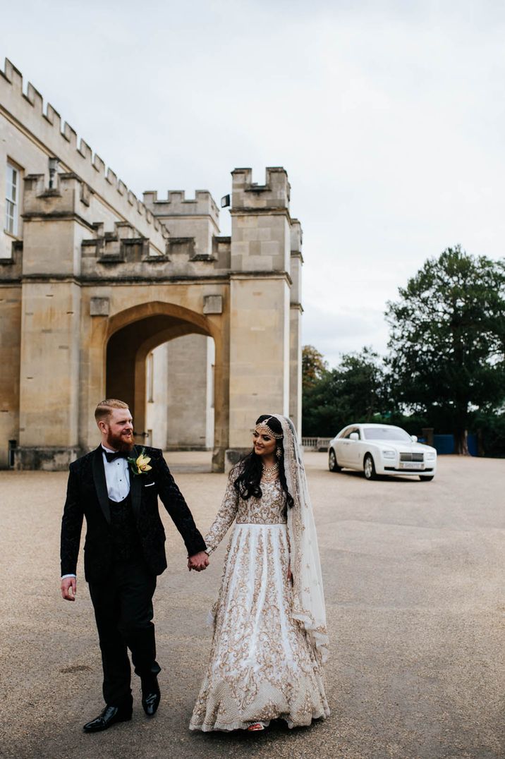 Groom in traditional black tie with the bride in an ivory and gold embroidered dress and veil for wedding under 40k 